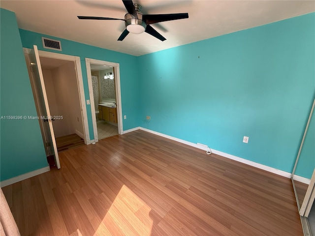 unfurnished bedroom with ensuite bathroom, hardwood / wood-style floors, and ceiling fan