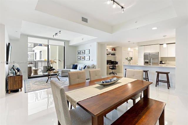 dining room featuring a raised ceiling and track lighting