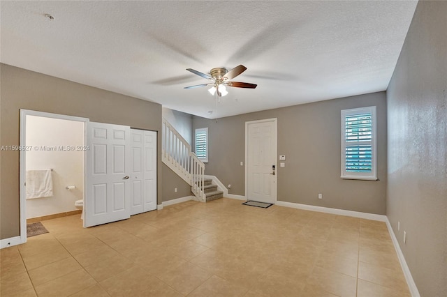 tiled spare room with a wealth of natural light, ceiling fan, and a textured ceiling