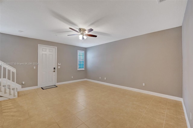 empty room with ceiling fan, light tile patterned flooring, and a textured ceiling