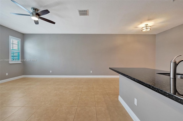 unfurnished room with ceiling fan, sink, light tile patterned flooring, and a textured ceiling