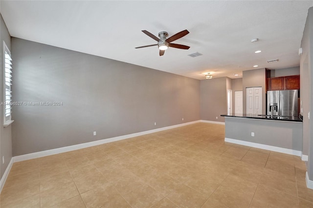 unfurnished living room featuring a wealth of natural light, ceiling fan, and light tile patterned floors