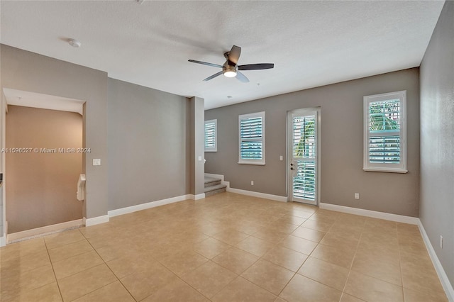 tiled spare room with ceiling fan and a textured ceiling