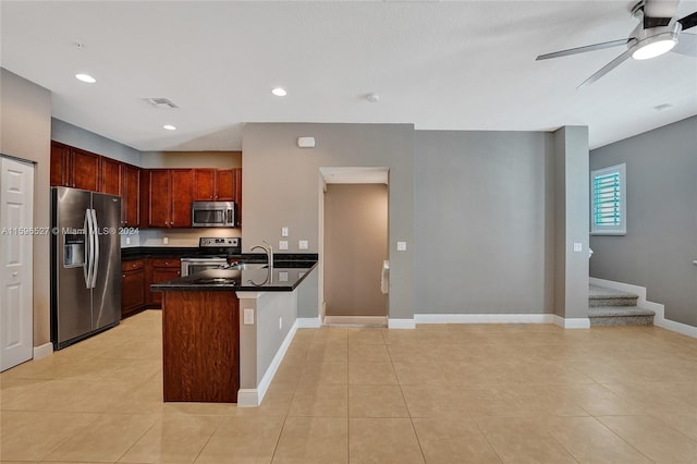 kitchen with kitchen peninsula, light tile patterned floors, stainless steel appliances, and ceiling fan