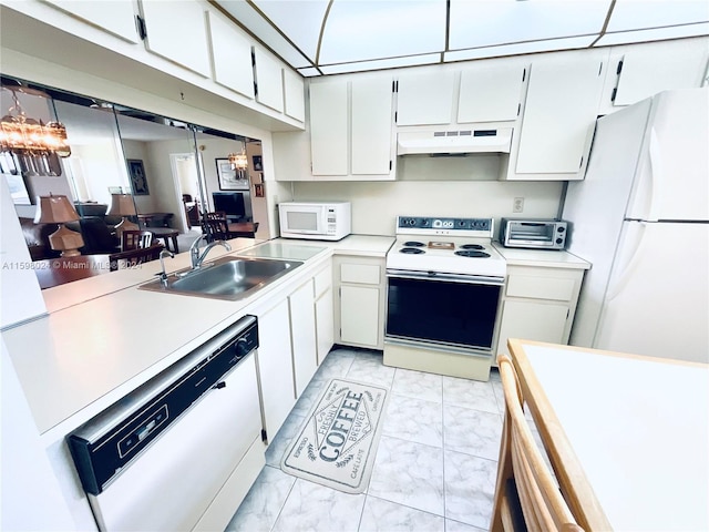 kitchen with white appliances, white cabinetry, a notable chandelier, and sink