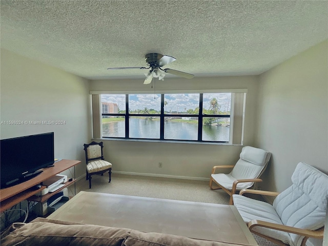 sitting room featuring ceiling fan, a healthy amount of sunlight, a water view, and carpet floors