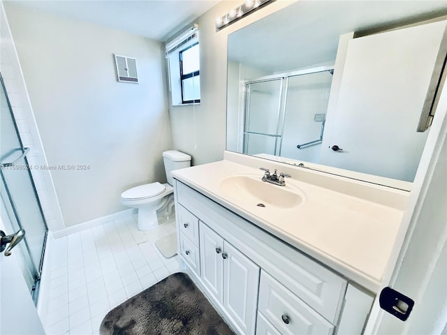 bathroom with tile patterned flooring, vanity, toilet, and a shower with door