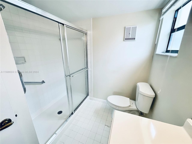 bathroom with tile patterned floors, toilet, and a shower with door