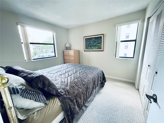 carpeted bedroom featuring a textured ceiling and a closet