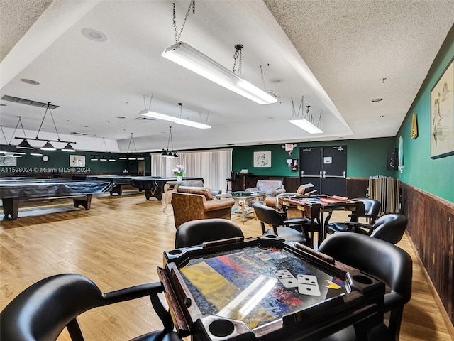 interior space with hardwood / wood-style floors, wood walls, a textured ceiling, and billiards