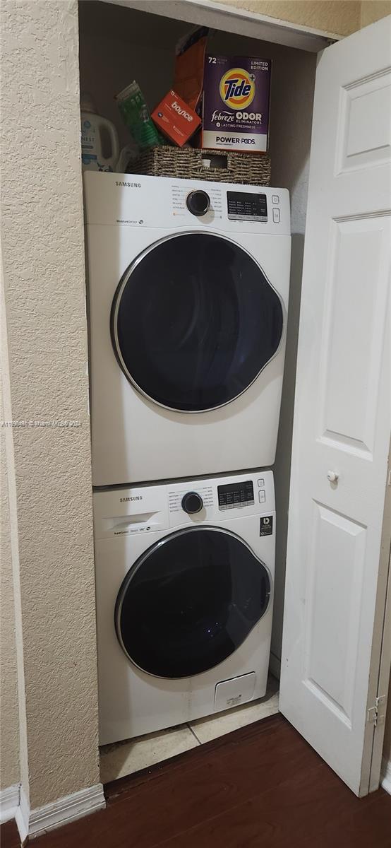 laundry room with stacked washer / dryer and dark wood-type flooring