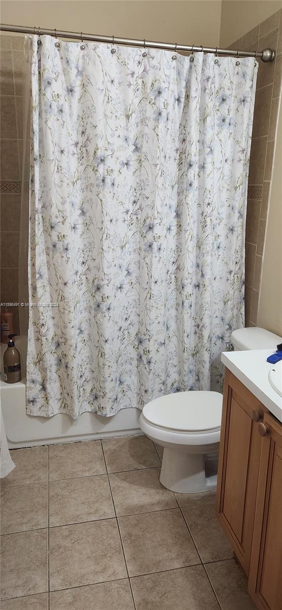 full bathroom with tile patterned floors, vanity, shower / bath combo, and toilet