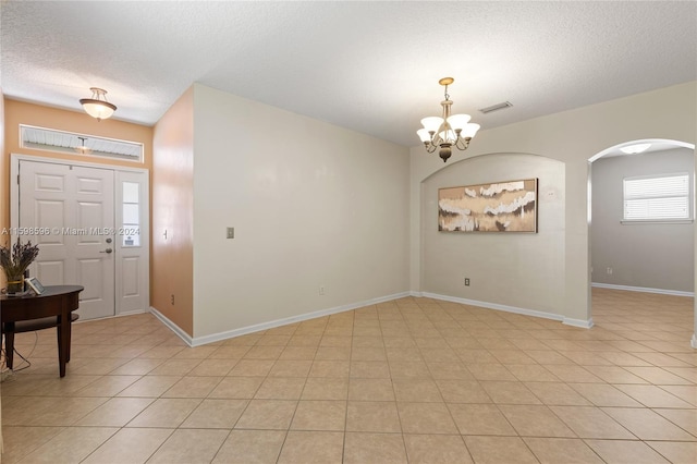 tiled entryway featuring a notable chandelier and a textured ceiling