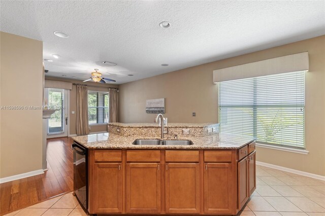 kitchen featuring light tile patterned floors, dishwasher, a kitchen island with sink, ceiling fan, and sink