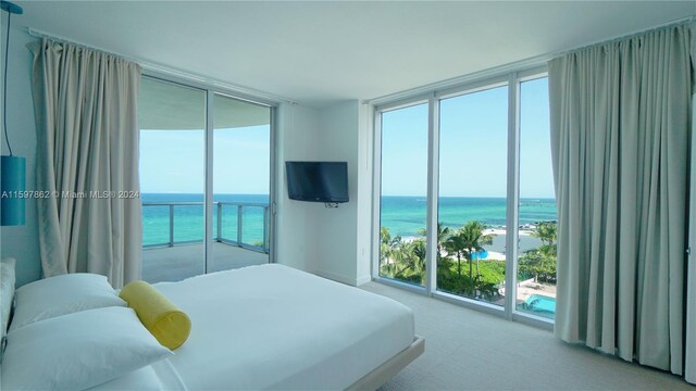 bedroom with floor to ceiling windows, a water view, access to exterior, and carpet floors