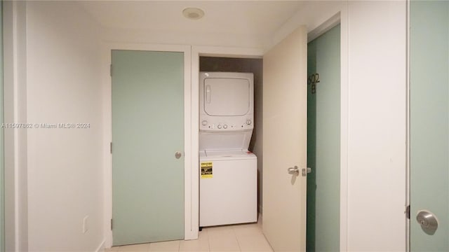 clothes washing area featuring light tile floors and stacked washer / drying machine