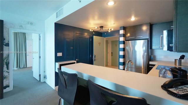 kitchen featuring carpet, kitchen peninsula, and stainless steel refrigerator