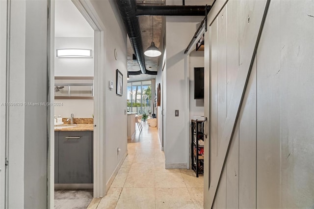 hallway with a barn door, light tile patterned floors, and sink