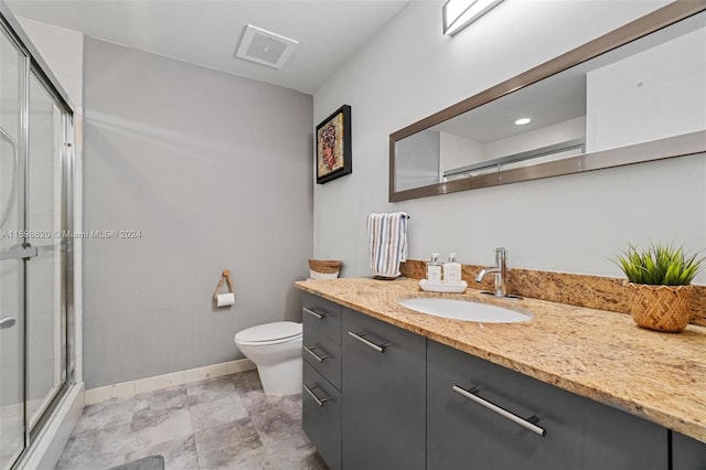 bathroom with vanity, a shower with shower door, and toilet