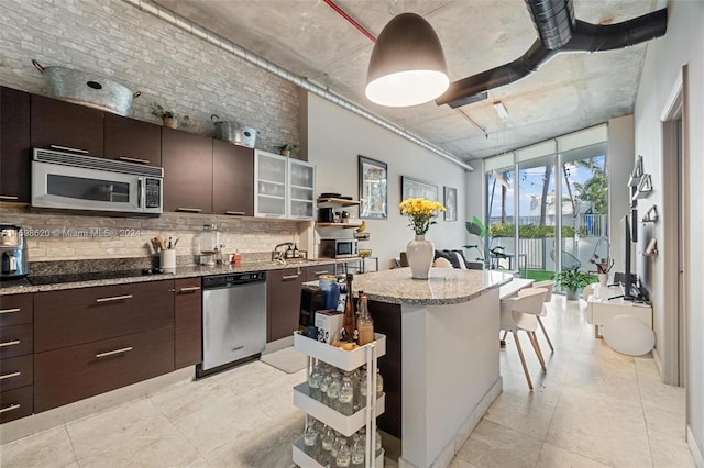 kitchen with dark brown cabinets, a center island, appliances with stainless steel finishes, and tasteful backsplash