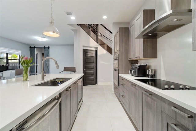 kitchen with dishwasher, hanging light fixtures, wall chimney range hood, a barn door, and black electric stovetop