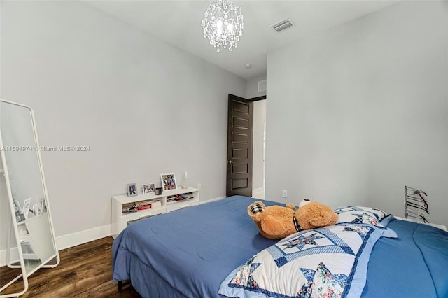 bedroom with dark hardwood / wood-style floors and an inviting chandelier