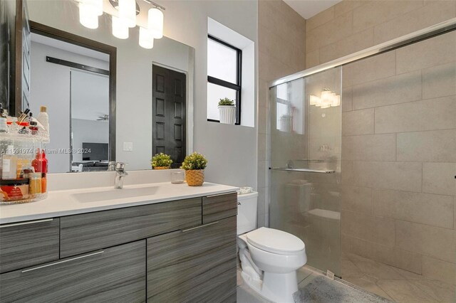 bathroom featuring an enclosed shower, vanity, toilet, and tile patterned flooring