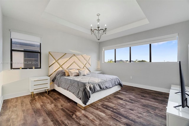 bedroom with a raised ceiling, dark hardwood / wood-style flooring, and a chandelier