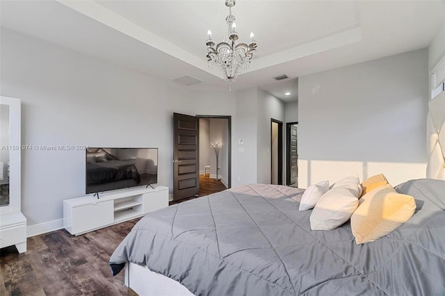 bedroom with a raised ceiling, dark hardwood / wood-style flooring, and an inviting chandelier