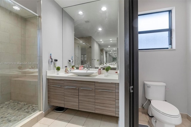 bathroom featuring tile patterned floors, vanity, toilet, and a shower with shower door