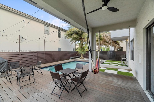 wooden terrace with ceiling fan, area for grilling, and a fenced in pool