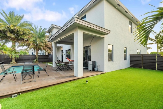 rear view of house featuring a lawn and a swimming pool side deck