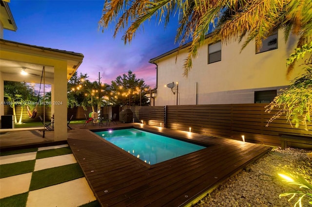 pool at dusk featuring a wooden deck