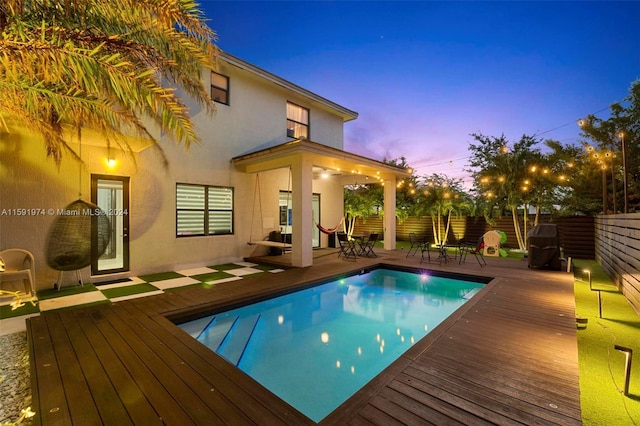 pool at dusk featuring a wooden deck