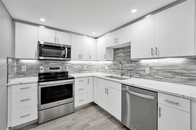 kitchen with backsplash, sink, white cabinets, and stainless steel appliances