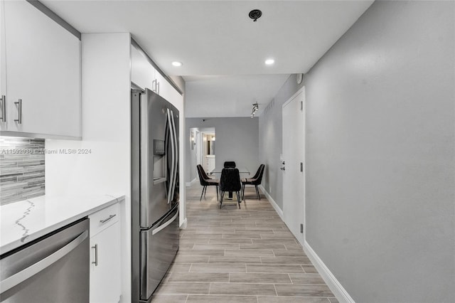 kitchen featuring decorative backsplash, white cabinetry, light hardwood / wood-style floors, and appliances with stainless steel finishes