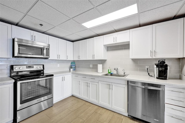 kitchen featuring a drop ceiling, white cabinetry, sink, and appliances with stainless steel finishes