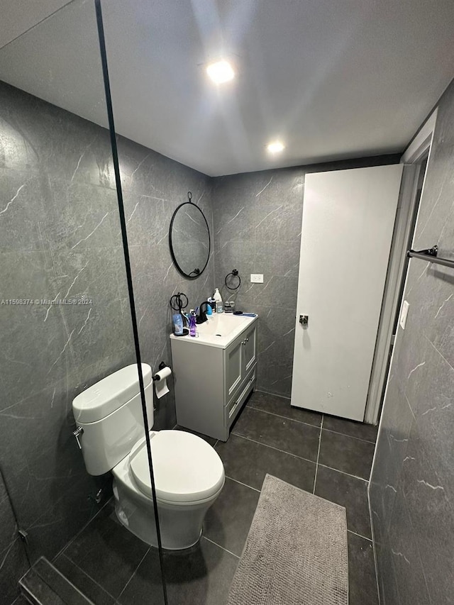 bathroom featuring tile walls, tile flooring, vanity, and toilet