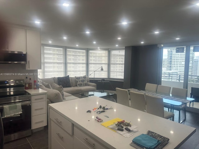 kitchen featuring white cabinetry, a kitchen island, appliances with stainless steel finishes, a breakfast bar, and dark tile flooring