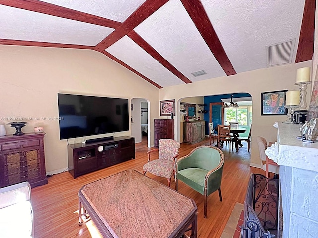 living room with vaulted ceiling, a textured ceiling, and light hardwood / wood-style flooring