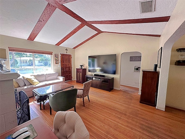 living room featuring vaulted ceiling with beams, a textured ceiling, and light hardwood / wood-style flooring