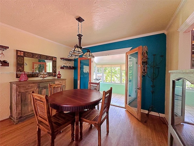 dining area featuring wood-type flooring, ornamental molding, french doors, and a textured ceiling