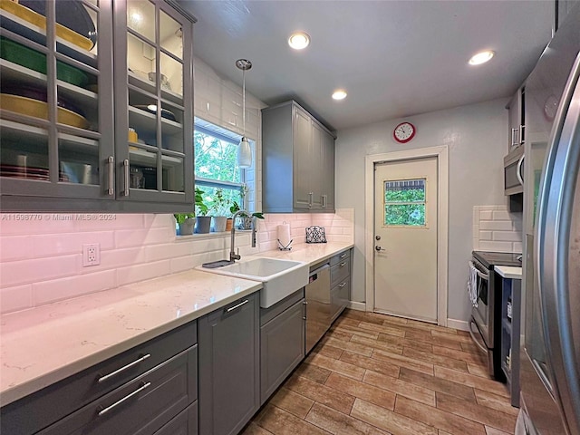 kitchen featuring appliances with stainless steel finishes, sink, pendant lighting, and decorative backsplash