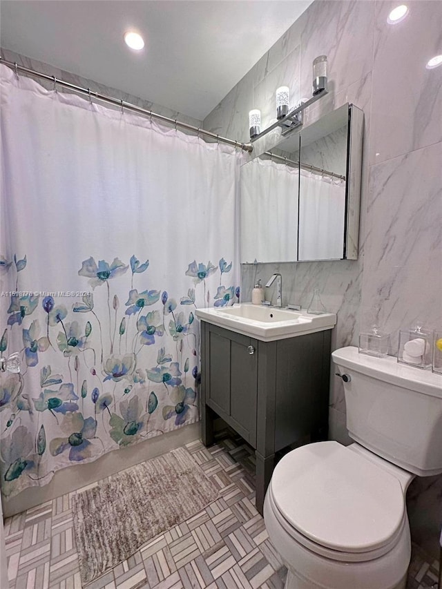 bathroom with vanity, tile walls, and toilet