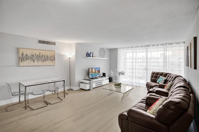 living room with floor to ceiling windows, a textured ceiling, and light hardwood / wood-style flooring