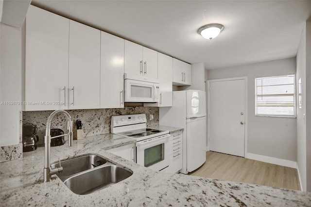 kitchen featuring white appliances, white cabinetry, sink, light wood-type flooring, and light stone counters