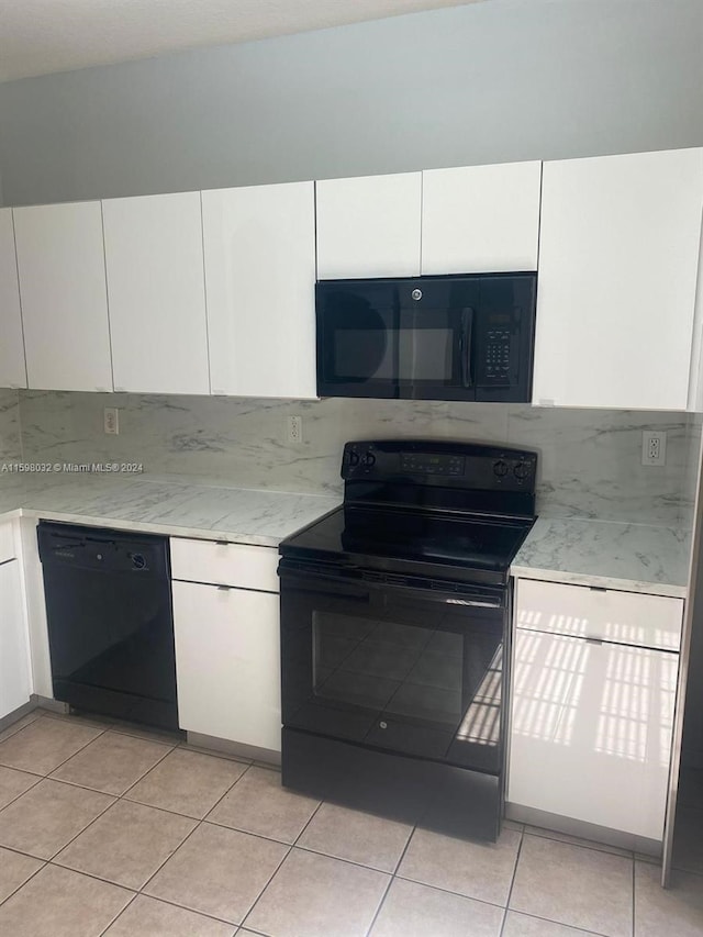 kitchen with black appliances, white cabinets, light stone countertops, and light tile patterned flooring