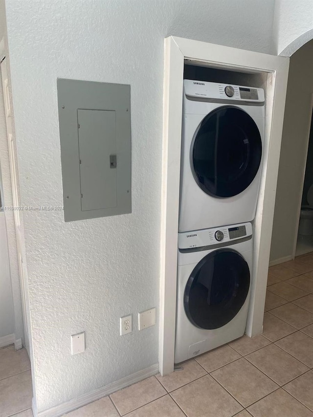 laundry room with light tile patterned floors, electric panel, and stacked washer / dryer