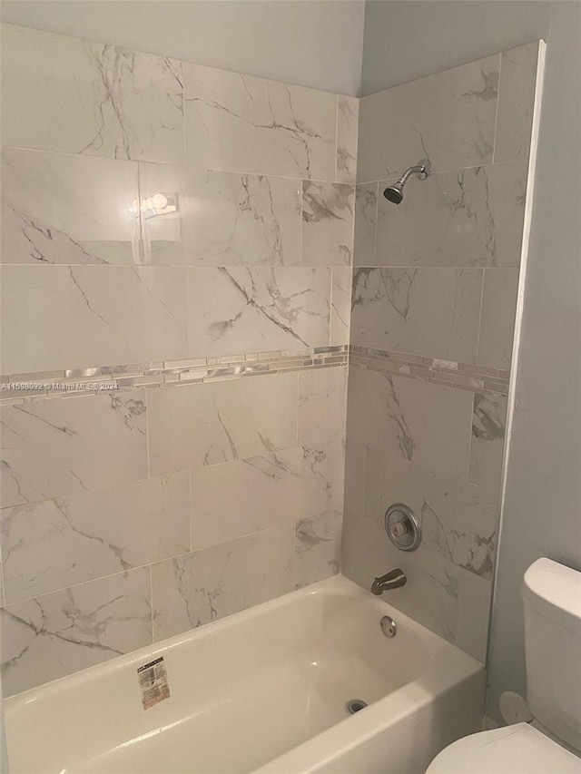 bathroom featuring toilet and tiled shower / bath combo