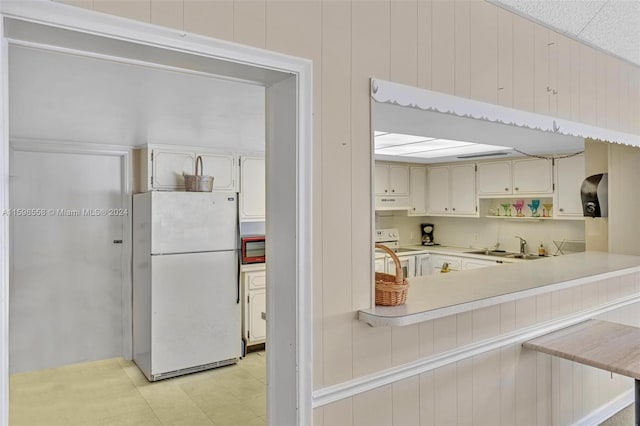 kitchen with sink, a kitchen breakfast bar, range hood, kitchen peninsula, and white appliances